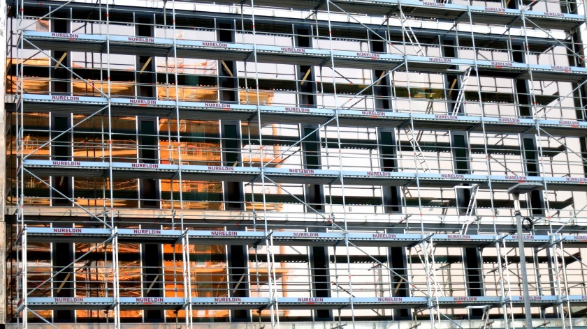 Fensterfront eines Neubaus hinter Baugerüst